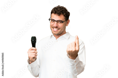 Brazilian man picking up a microphone over isolated chroma key background making money gesture