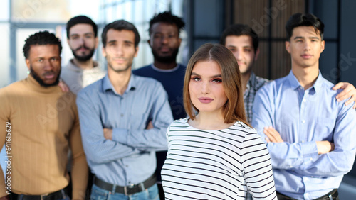 Successful millennial business woman stands at the forefront of a multiethnic team
