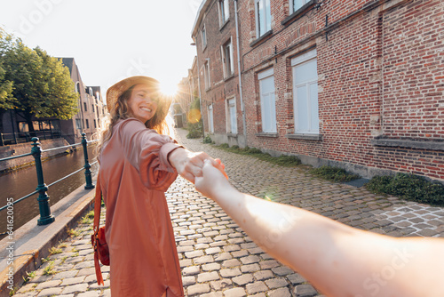 Obraz na płótnie follow me concept - happy smiling woman holding hand of girlfriend in old downto