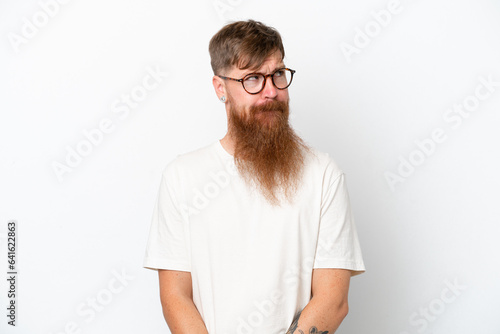 Redhead man with long beard isolated on white background having doubts while looking up © luismolinero