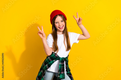 Photo portrait of charming schoolgirl excited showing double v-sign banner wear trendy white garment isolated on yellow color background