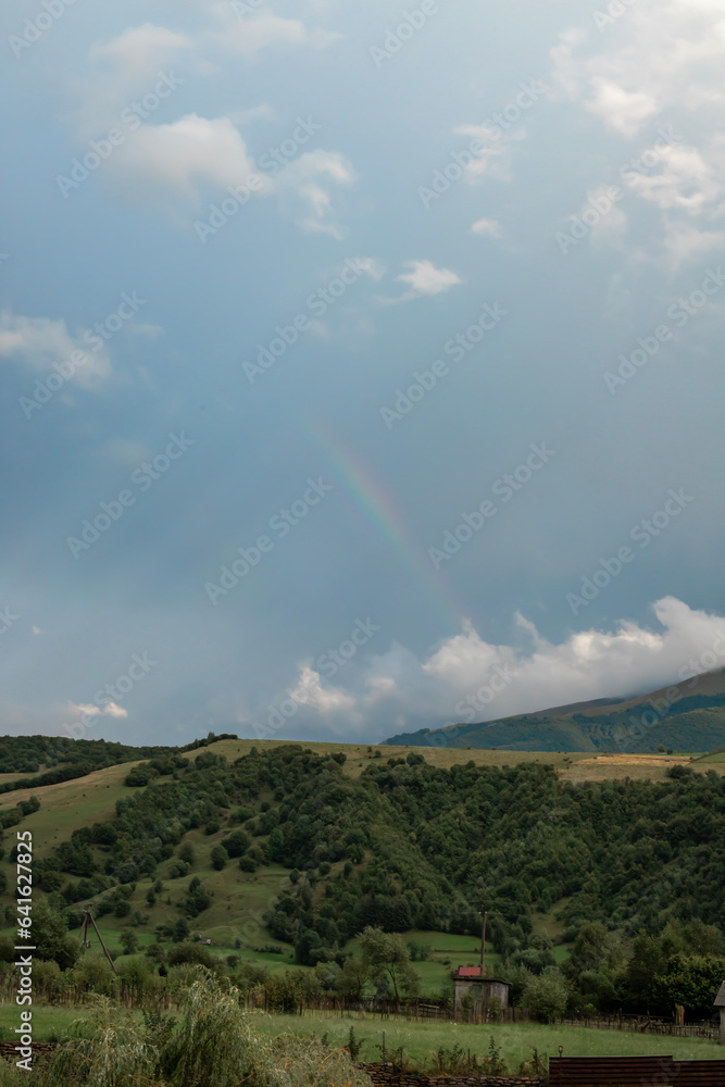 Mountain landscape in cloudy weather and rainbow among clouds Mountain landscape in cloudy weather and rainbow among clouds