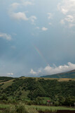 Mountain landscape in cloudy weather and rainbow among clouds 