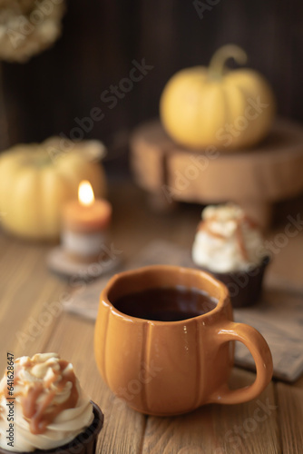 A cozy still life with a cup in the form of a pumpkin, a candle and small pumpkins