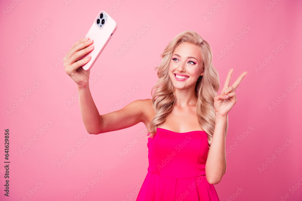 Photo of stunning positive person hold smart phone make selfie demonstrate v-sign isolated on pink color background Photo of stunning positive person hold smart phone make selfie demonstrate v-sign isolated on pink color background