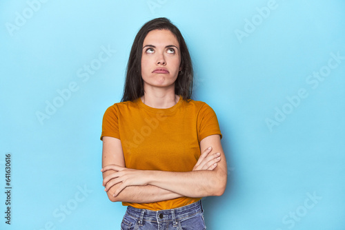 Young caucasian woman on blue backdrop tired of a repetitive task.
