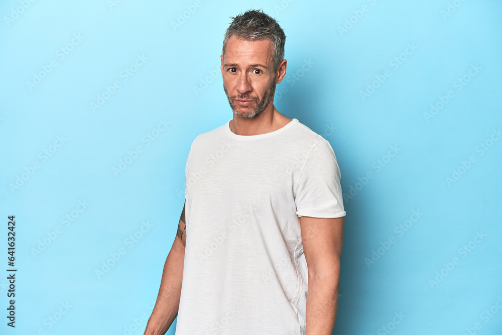Middle-aged man posing on blue studio backdrop Middle-aged man posing on blue studio backdrop