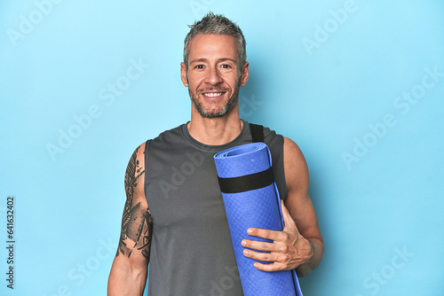 Canvastavla Athlete holding a fitness mat on blue studio background