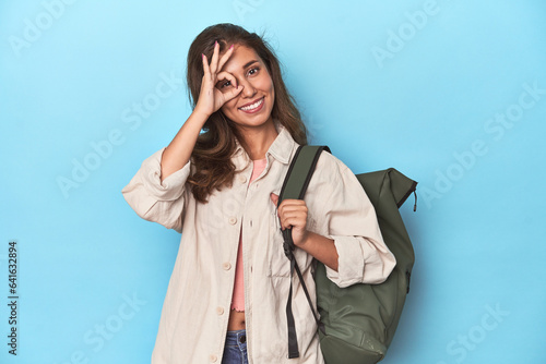 Young adventurer ready to explore with backpack excited keeping ok gesture on eye. photo