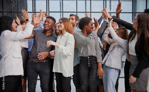 Excited multinational employees celebrating team victory giving high five gathered in office,