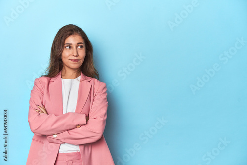 Teen girl in pink suit, arms crossed, with space on one side.