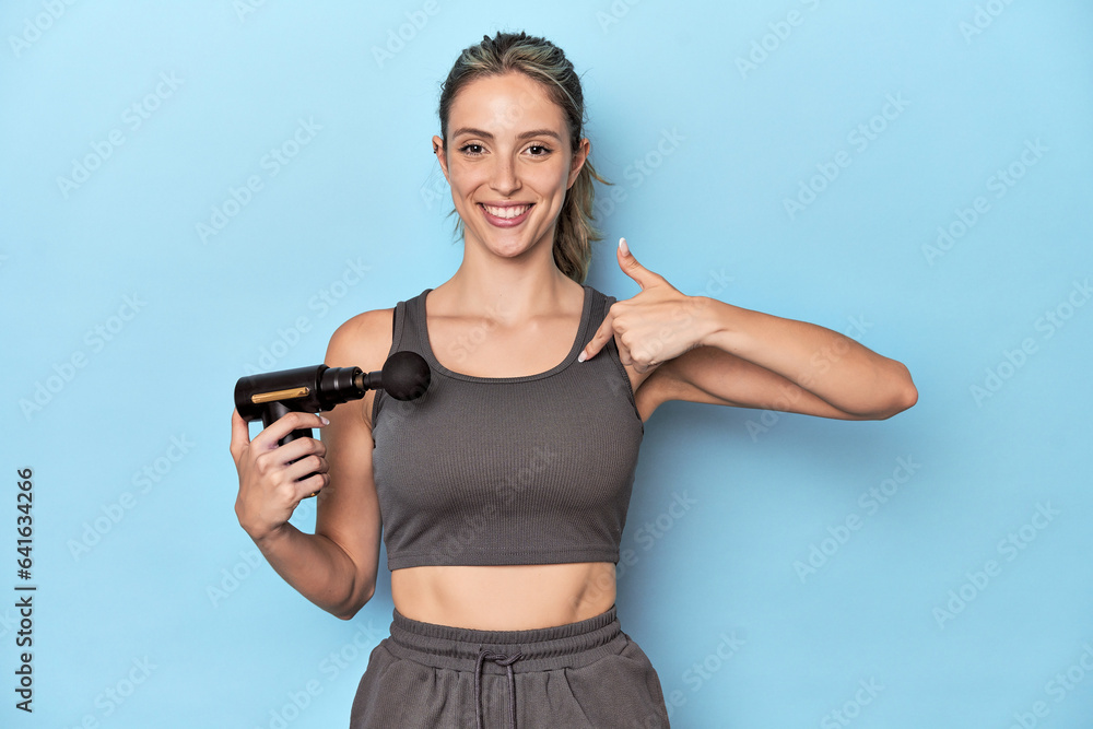 Athlete holding an electric massager person pointing by hand to a shirt copy space, proud and confident Athlete holding an electric massager person pointing by hand to a shirt copy space, proud and confident