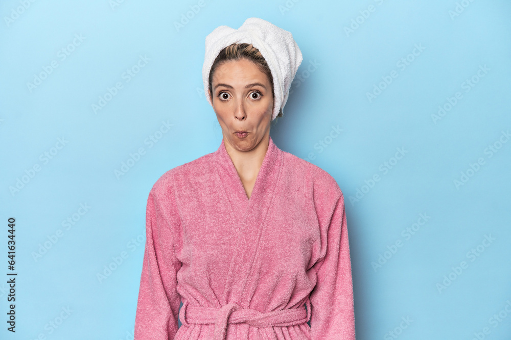 Woman in pink robe after shower shrugs shoulders and open eyes confused. Woman in pink robe after shower shrugs shoulders and open eyes confused.