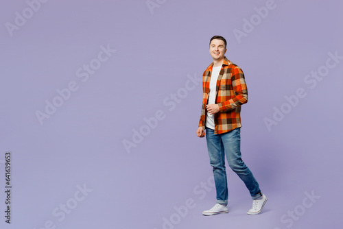 Full body young happy man he wears checkered shirt white t-shirt casual clothes walking going look camera strolling isolated on plain pastel light purple background studio portrait. Lifestyle concept.