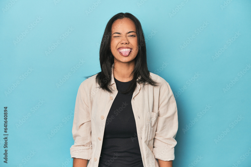 Obraz premium Filipina young woman on blue studio funny and friendly sticking out tongue.