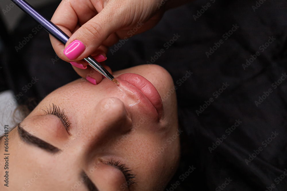 Applying foundation on the lip contour before the permanent makeup procedure. Delicate permanent lip makeup for blondes Applying foundation on the lip contour before the permanent makeup procedure. Delicate permanent lip makeup for blondes