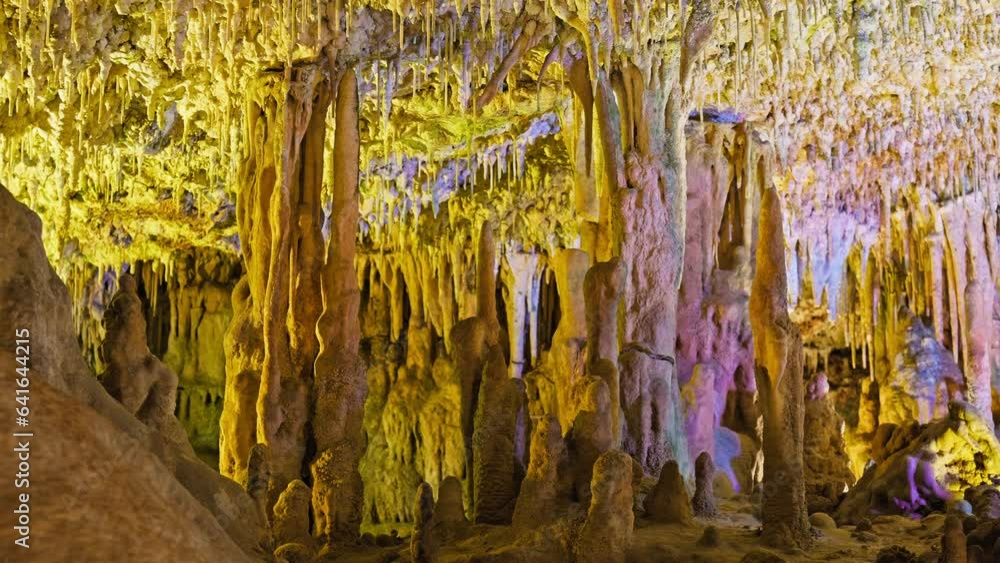 Underground cave with distinct rocky formations of stalactites and stalagmites. A colourful natural scenery in a cave with ancient cavities formed of carbonate limestone rocks in Mallorca, Spain. Underground cave with distinct rocky formations of stalactites and stalagmites. A colourful natural scenery in a cave with ancient cavities formed of carbonate limestone rocks in Mallorca, Spain.