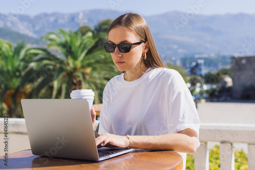 Work from a summer cafe. A young woman is working on a laptop. Businesswoman