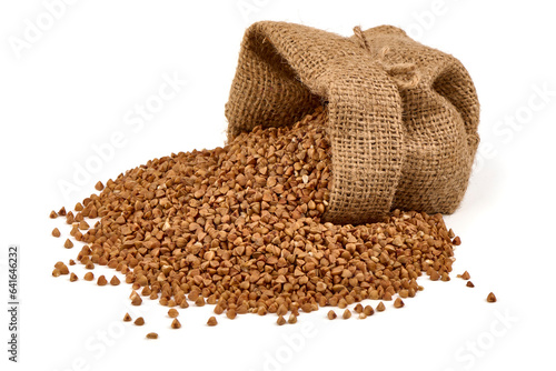 Raw buckwheat grains in rustic burlap isolated on white background. © GSDesign