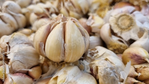 White garlic pile texture. Fresh garlic on market table closeup photo. Vitamin healthy food spice image. Spicy cooking ingredient picture. Pile of white garlic heads. Top view with copy space.