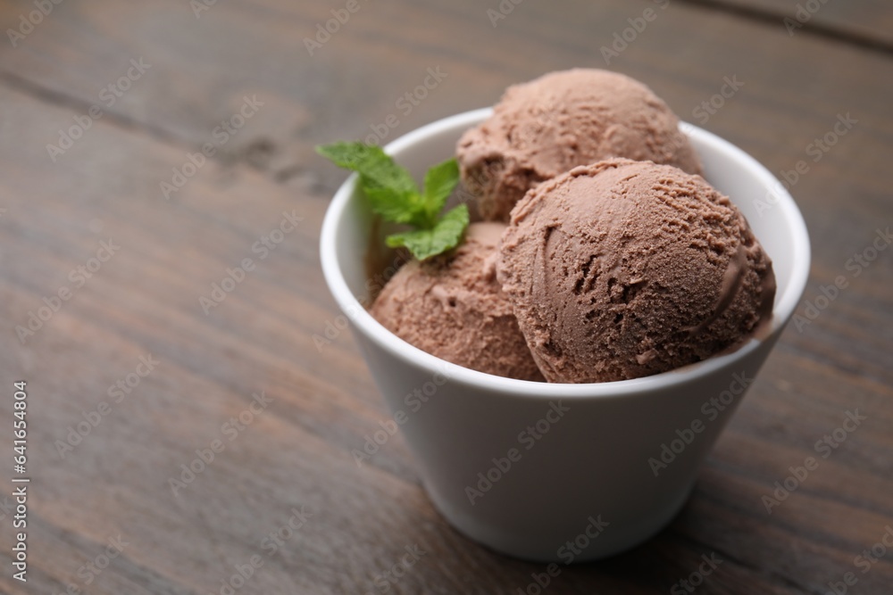 Bowl with tasty chocolate ice cream and mint leaves on wooden table. Space for text Bowl with tasty chocolate ice cream and mint leaves on wooden table. Space for text