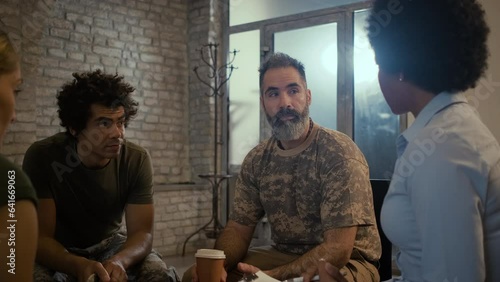 Group of diverse veterans talking during PTSD support group.