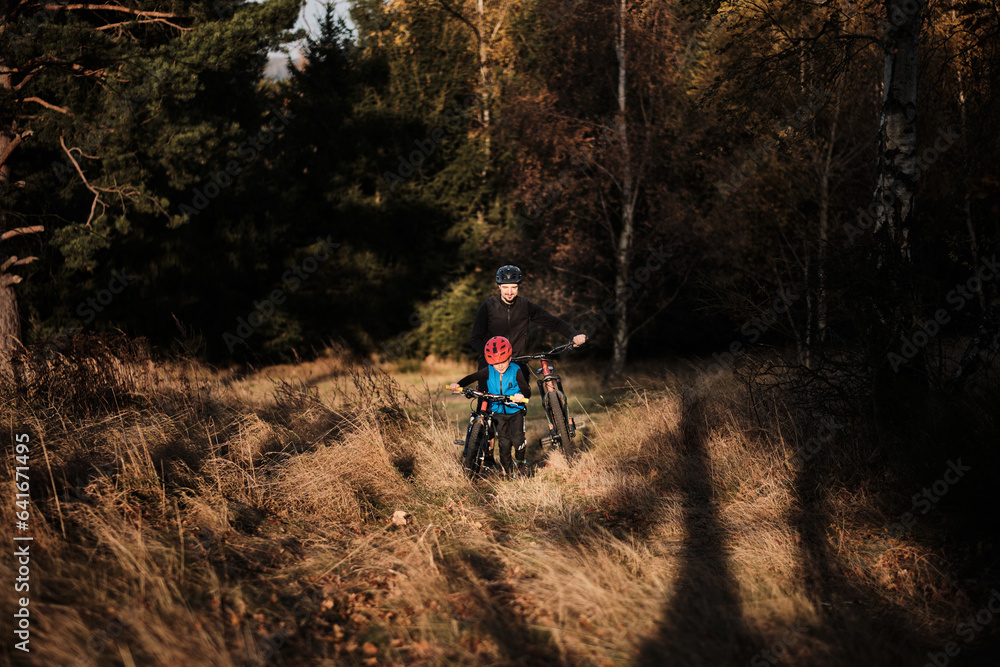 Obraz premium Father and son mountain biking on path in woods