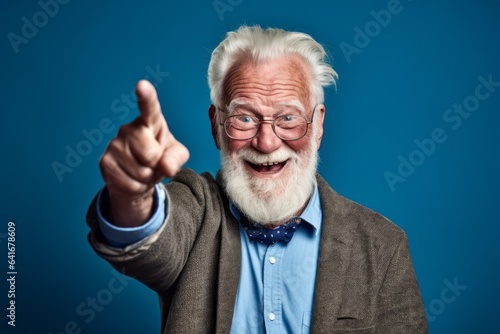 Headshot portrait photography of a grinning old man making a i see you gesture pointing at one's eyes against a soft blue background. With generative AI technology
