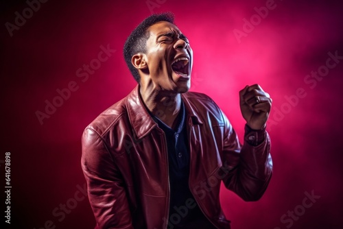 Lifestyle portrait photography of a joyful boy in his 30s dancing and singing song in microphone against a rich maroon background. With generative AI technology