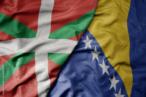 big waving national colorful flag of basque country and national flag of bosnia and herzegovina .