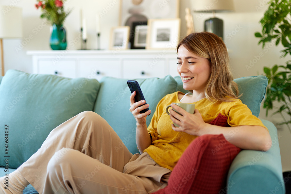 Woman using smartphone while drinking coffee at her home in the morning Woman using smartphone while drinking coffee at her home in the morning