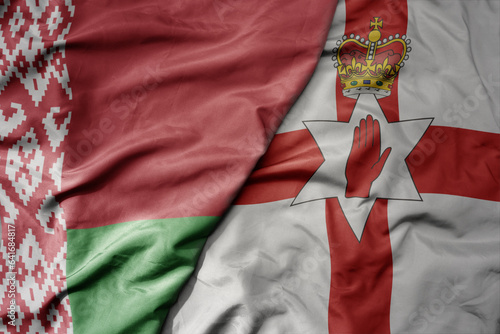 big waving national colorful flag of belarus and national flag of northern ireland .