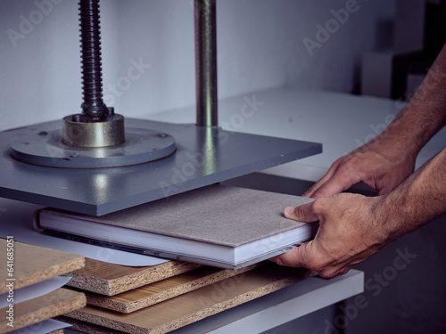 Tableau sur toile Bookmaker using press machine on new book at workplace