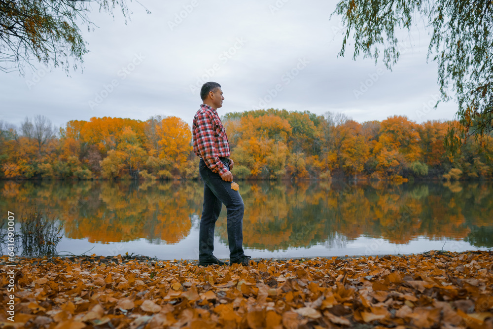 a man stands on the bank of the river and enjoys the scenery, beautiful nature in the autumn season, the river and the forest with bright yellow leaves, cloudy sky in the evening a man stands on the bank of the river and enjoys the scenery, beautiful nature in the autumn season, the river and the forest with bright yellow leaves, cloudy sky in the evening