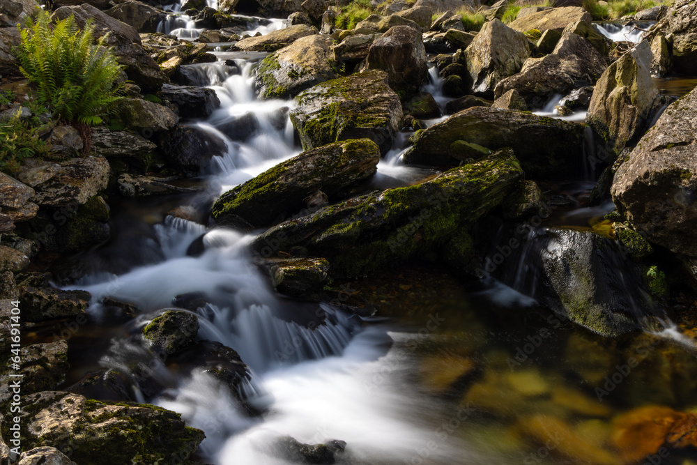 Long exposure image of a cascading mountain stream tumbling over moss covered rocks at Nant Peris, Snowdonia, Llan Beris Pass Wales Long exposure image of a cascading mountain stream tumbling over moss covered rocks at Nant Peris, Snowdonia, Llan Beris Pass Wales