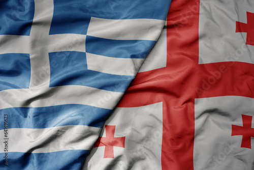 big waving national colorful flag of greece and national flag of georgia .