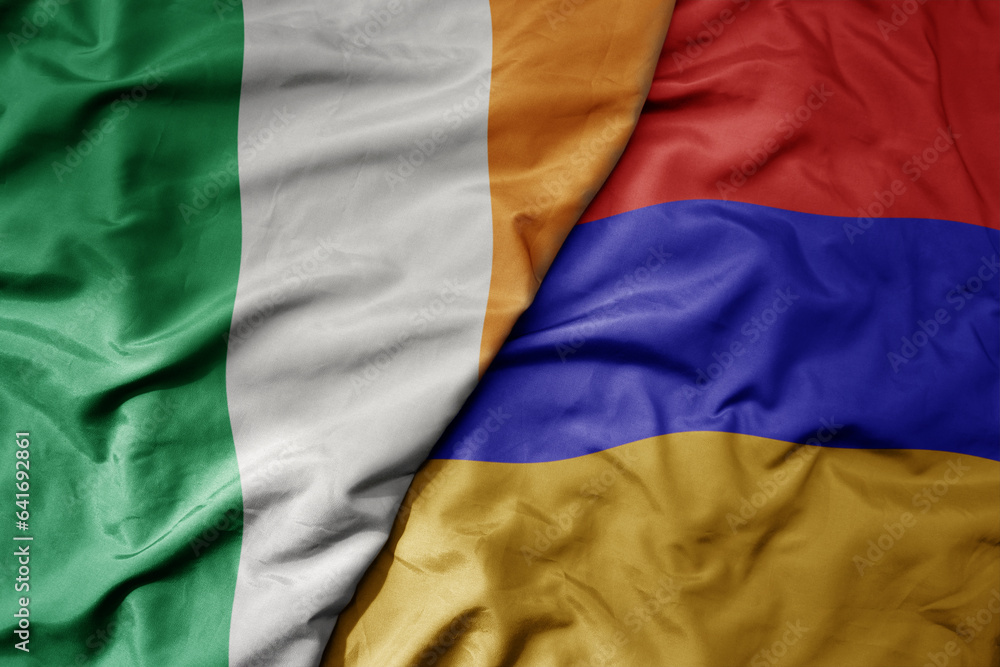 big waving national colorful flag of ireland and national flag of armenia .