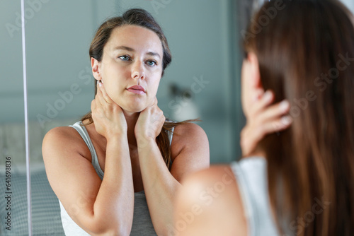 Upset woman standing front on mirror and thinking of her problems and depression photo