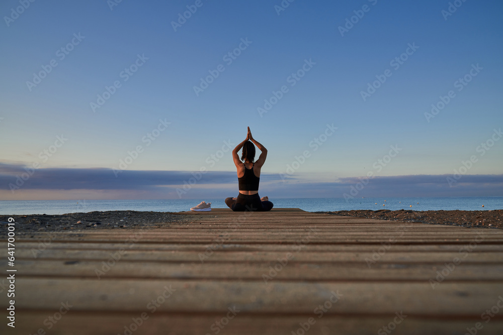 Unrecognizable woman meditating on beach