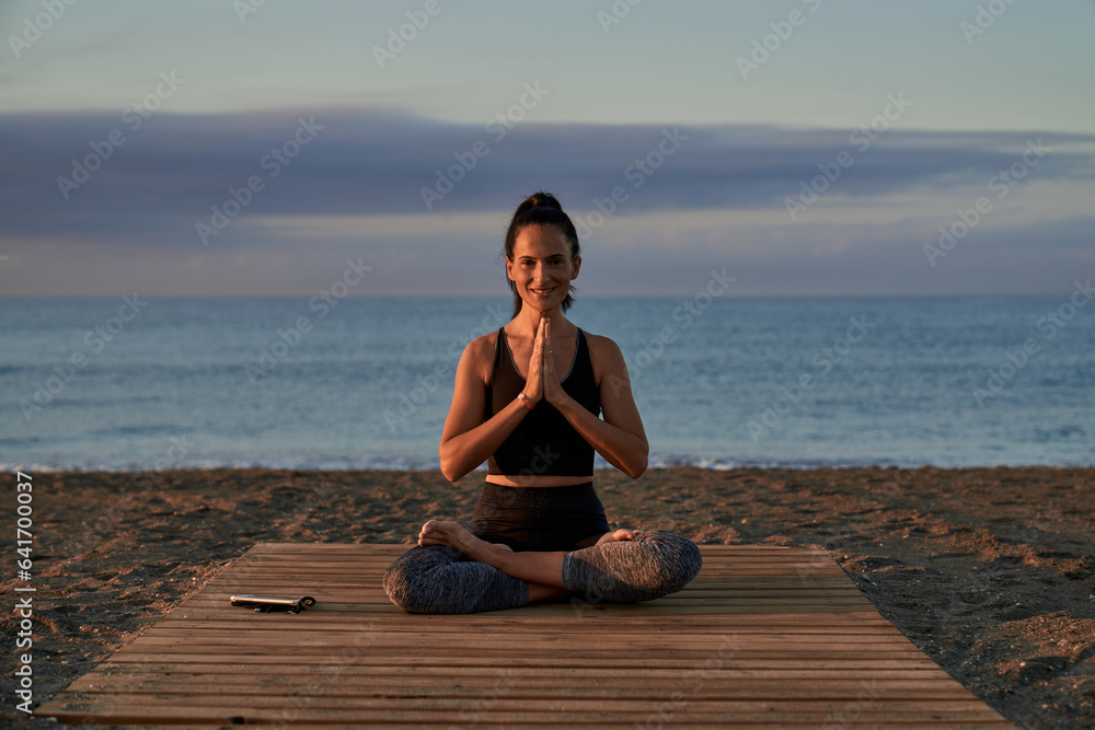 Positive Hispanic woman meditating on shore
