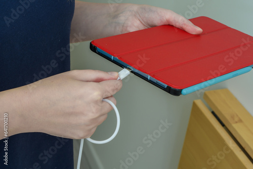 Kobieta wpinająca kabel od ładowarki USB do tableta