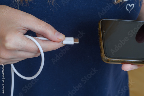 Kobieta podłączająca kabel od ładowarki USB typu c do telefonu