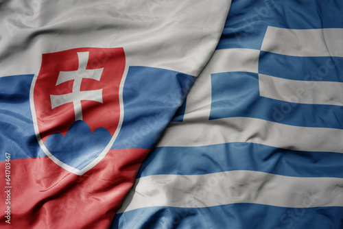 big waving national colorful flag of slovakia and national flag of greece .