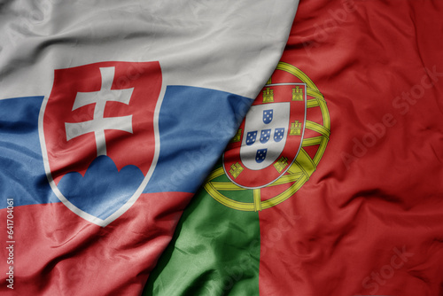 Photography big waving national colorful flag of slovakia and national flag of portugal