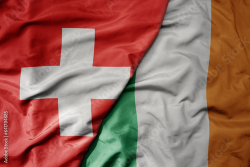 big waving national colorful flag of switzerland and national flag of ireland .