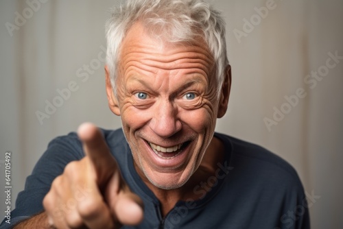 Close-up portrait photography of a grinning mature man making a i see you gesture pointing at one's eyes against a beige background. With generative AI technology