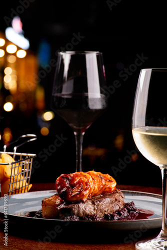 Obraz na plátně dinner table for two with two glasses of surf and turf white wine with blackberr