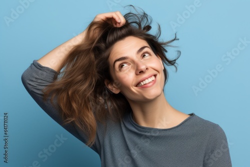 Close-up portrait photography of a joyful girl in her 30s scratching head in gesture of confusion against a periwinkle blue background. With generative AI technology