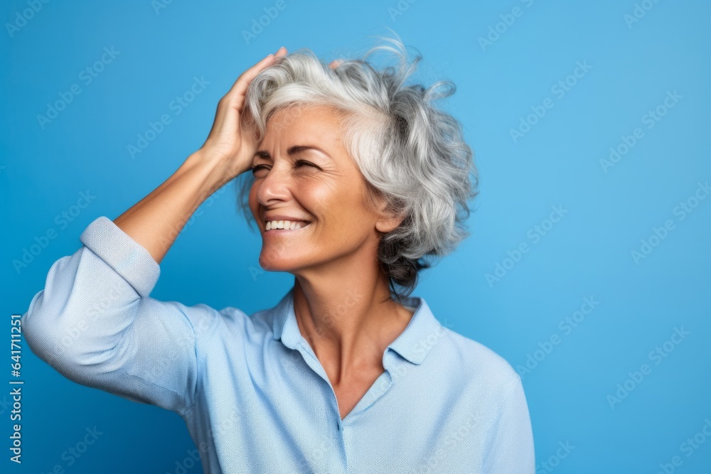 Lifestyle portrait photography of a joyful mature woman putting the hand on the forehead to look for someone in the distance against a periwinkle blue background. With generative AI technology