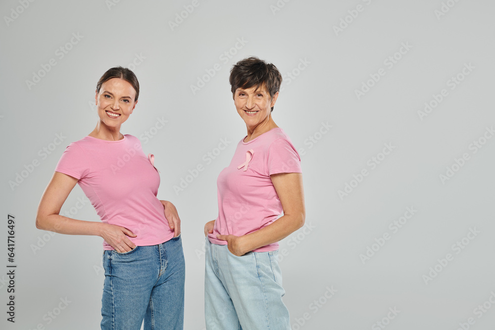 breast cancer concept, support campaign, two women looking at camera, smile, grey backdrop breast cancer concept, support campaign, two women looking at camera, smile, grey backdrop